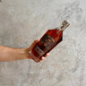Hand holding a bottle of Westward Whiskey Limited Edition Porter Cask against a gray concrete background