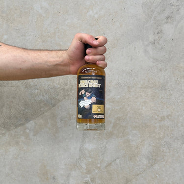 A hand holding a bottle of That boutique-y whisky company Ledaig 21 Year Old single malt Scotch whisky, with a label that includes the brand name and the batch number.